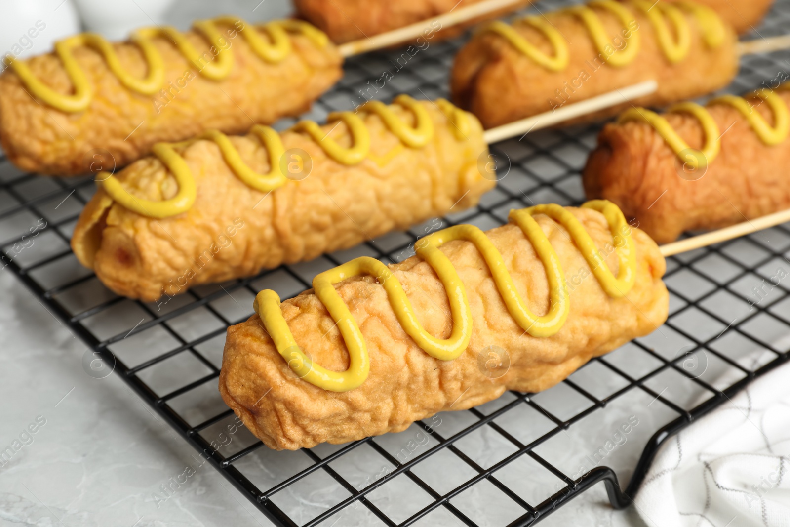 Photo of Delicious corn dogs with mustard on grey table, closeup