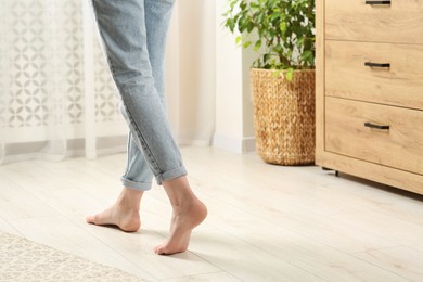 Woman stepping barefoot in room at home, closeup with space for text. Floor heating