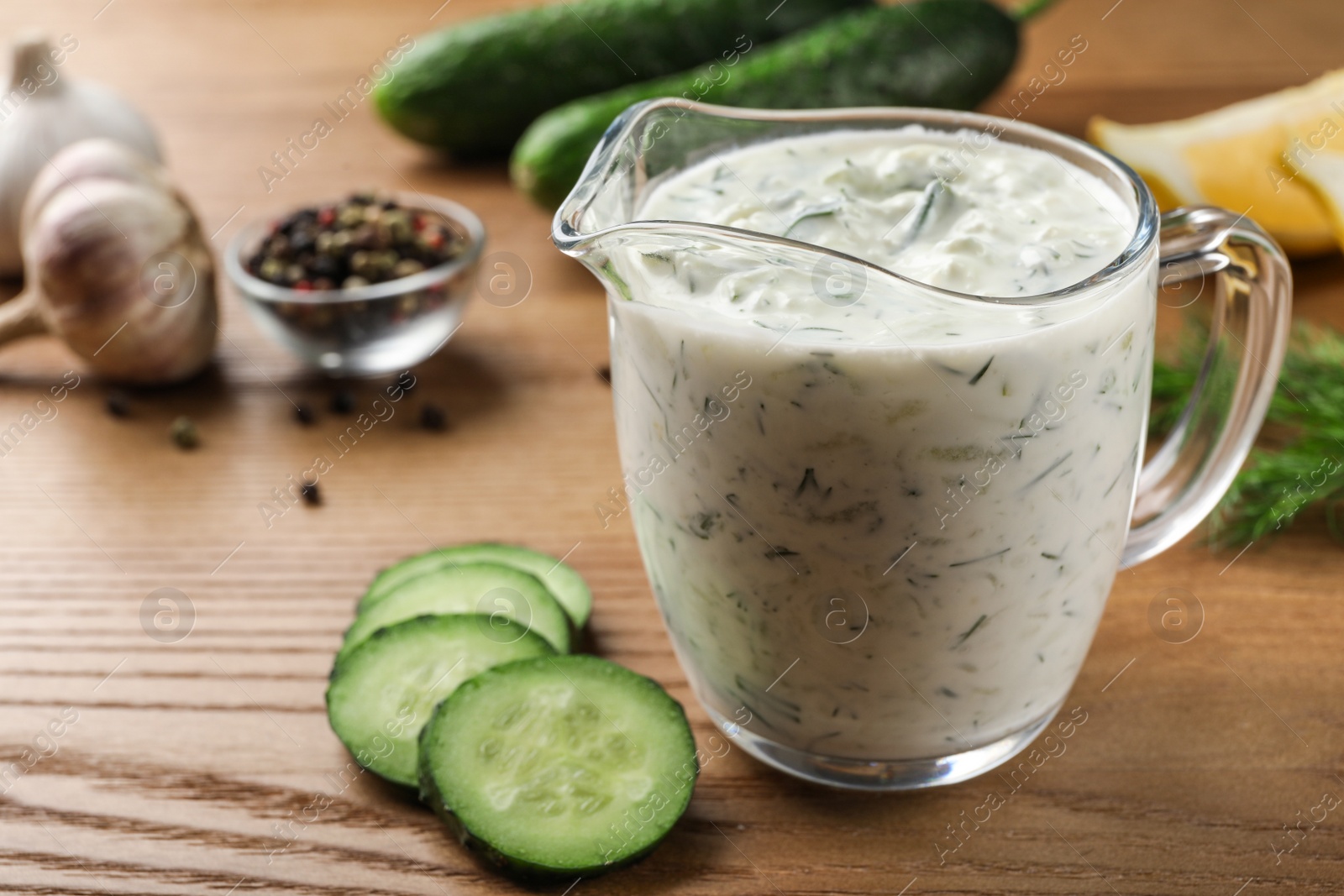 Photo of Cucumber sauce with ingredients on wooden background, space for text. Traditional Tzatziki