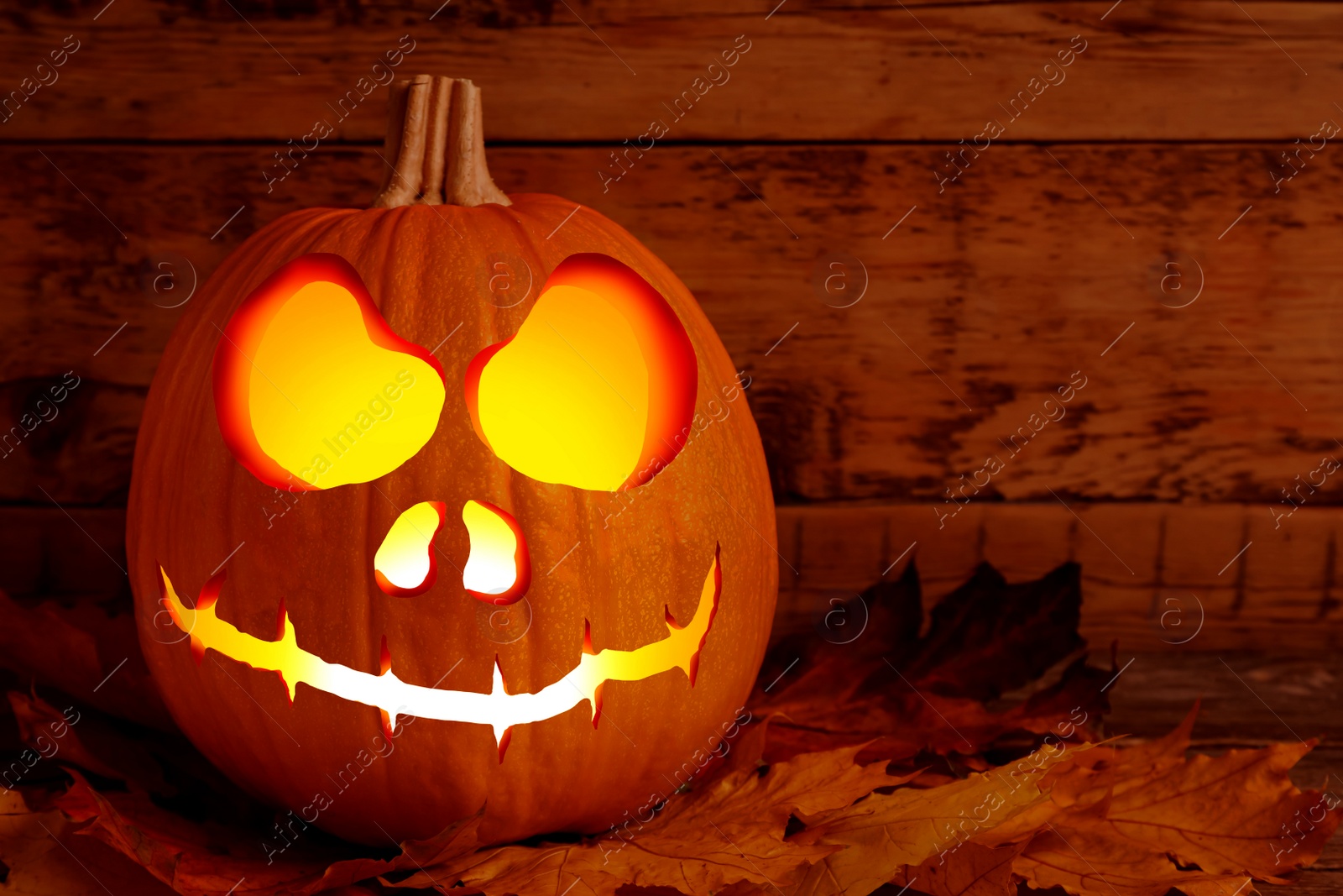 Image of Spooky jack o`lantern and dry autumn leaves on wooden table, space for text. Halloween decor