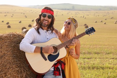 Beautiful hippie woman listening to her friend playing guitar in field