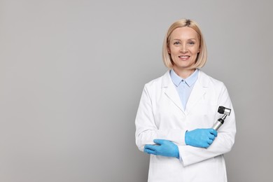 Happy dermatologist with dermatoscope on grey background, space for text