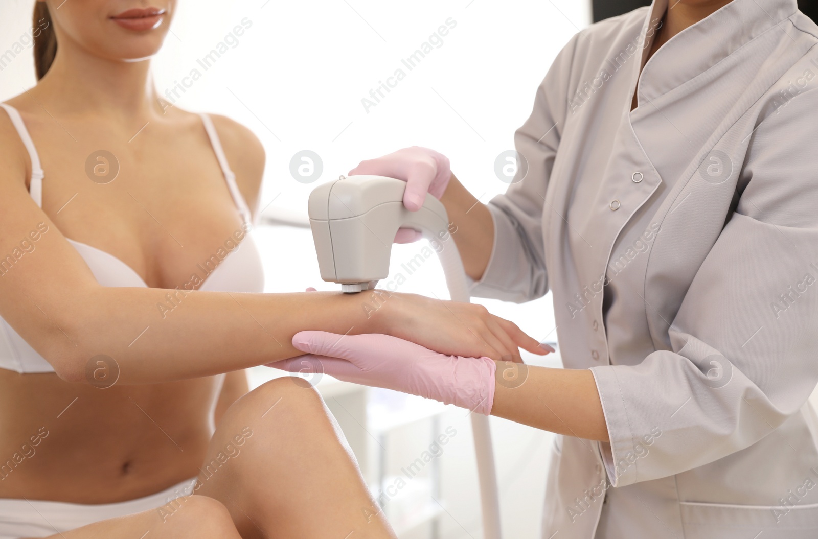 Photo of Young woman undergoing laser epilation procedure in beauty salon, closeup