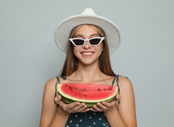 Beautiful girl with watermelon on grey background