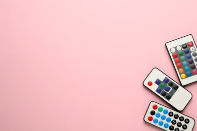 Different remote controls on pink background, flat lay. Space for text