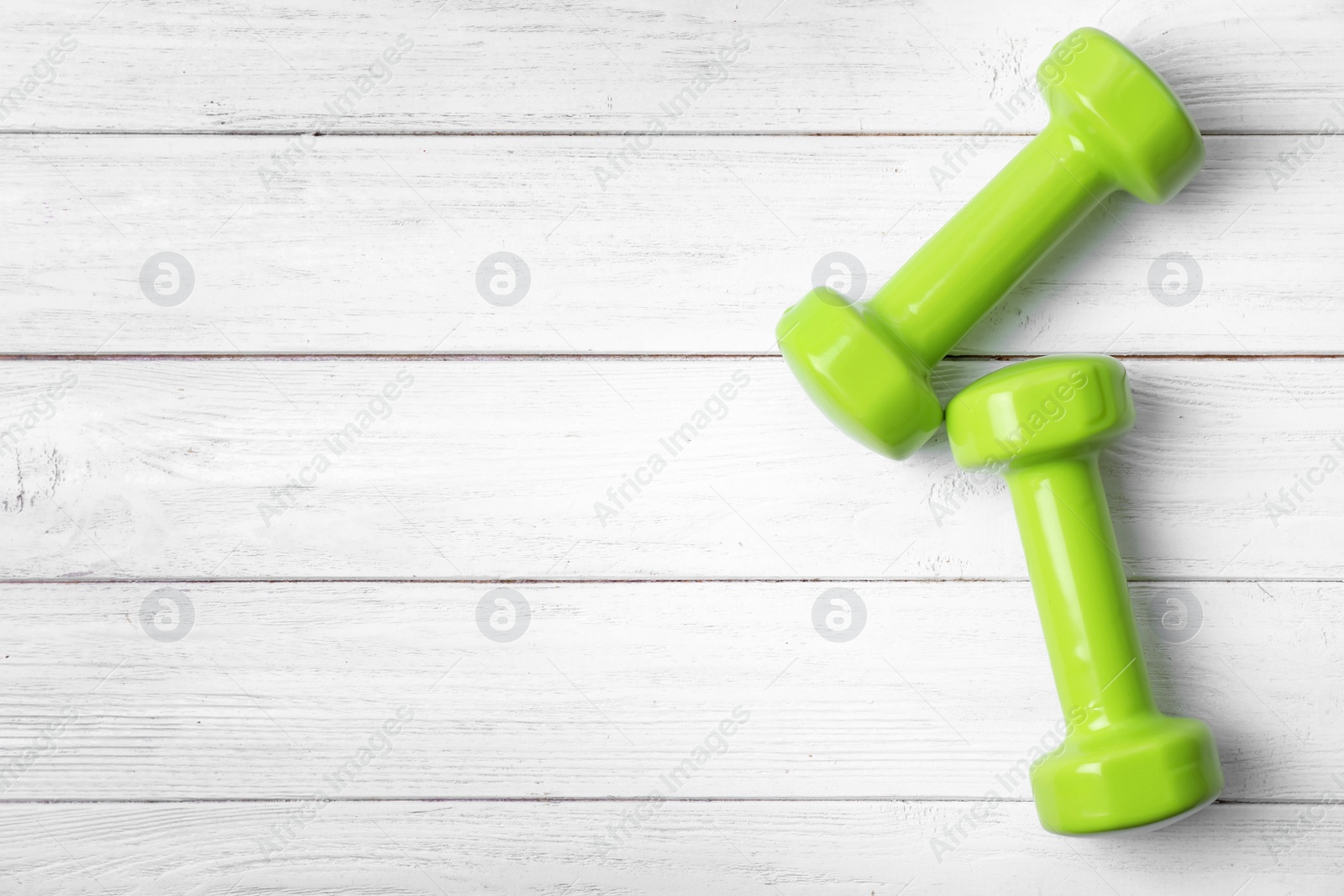 Photo of Bright dumbbells and space for text on wooden background, flat lay. Home fitness