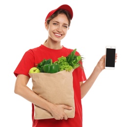 Photo of Delivery woman with bag of fresh vegetables and smartphone on white background, mockup for design