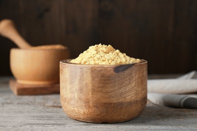 Photo of Bowl of mustard powder on wooden table, closeup