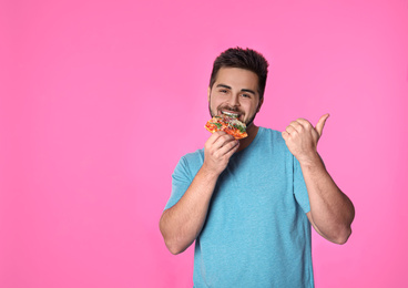 Photo of Handsome man with pizza on pink background, space for text