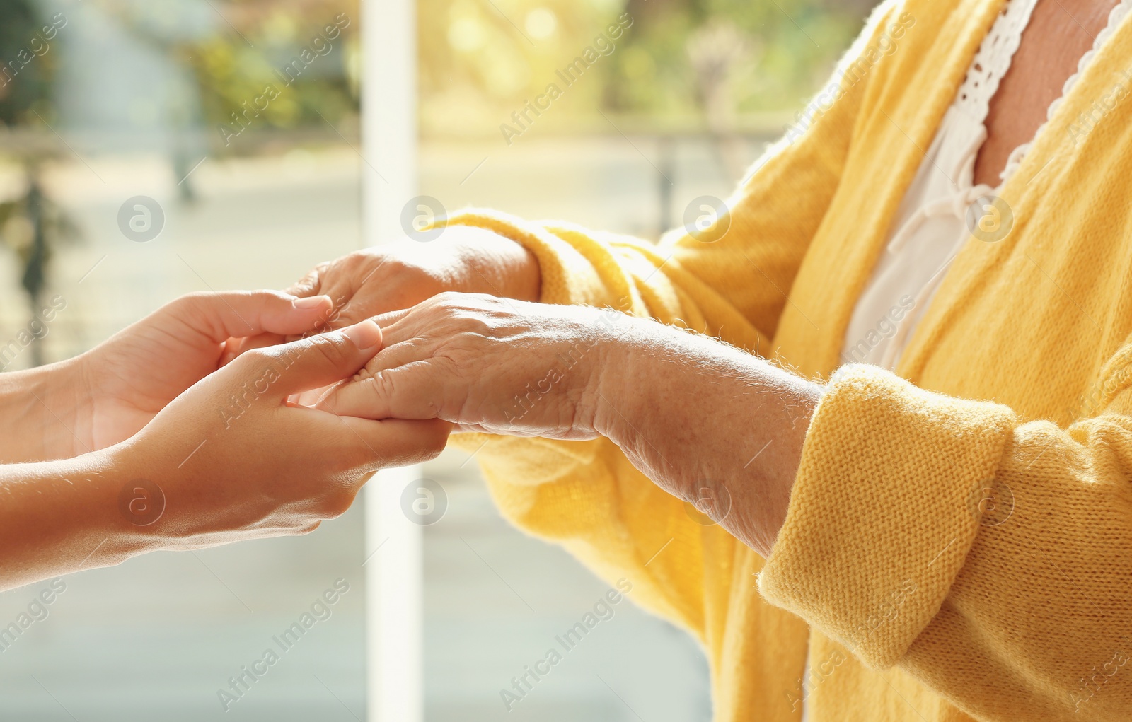 Photo of Helping hands on blurred background, closeup. Elderly care concept