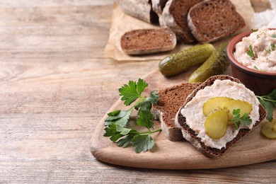 Photo of Sandwich with delicious lard spread and pickles on wooden table. Space for text