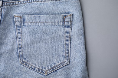 Jeans with pocket on grey background, top view