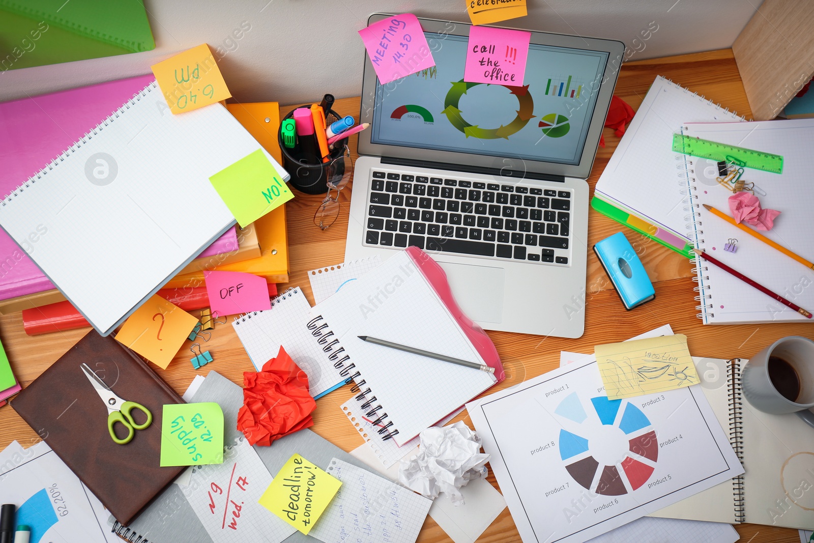 Photo of Messy table with laptop and sticky notes, above view. Concept of being overwhelmed by work