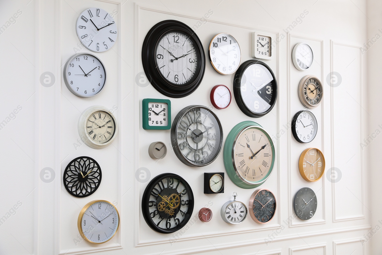 Photo of Collection of different clocks hanging on white wall