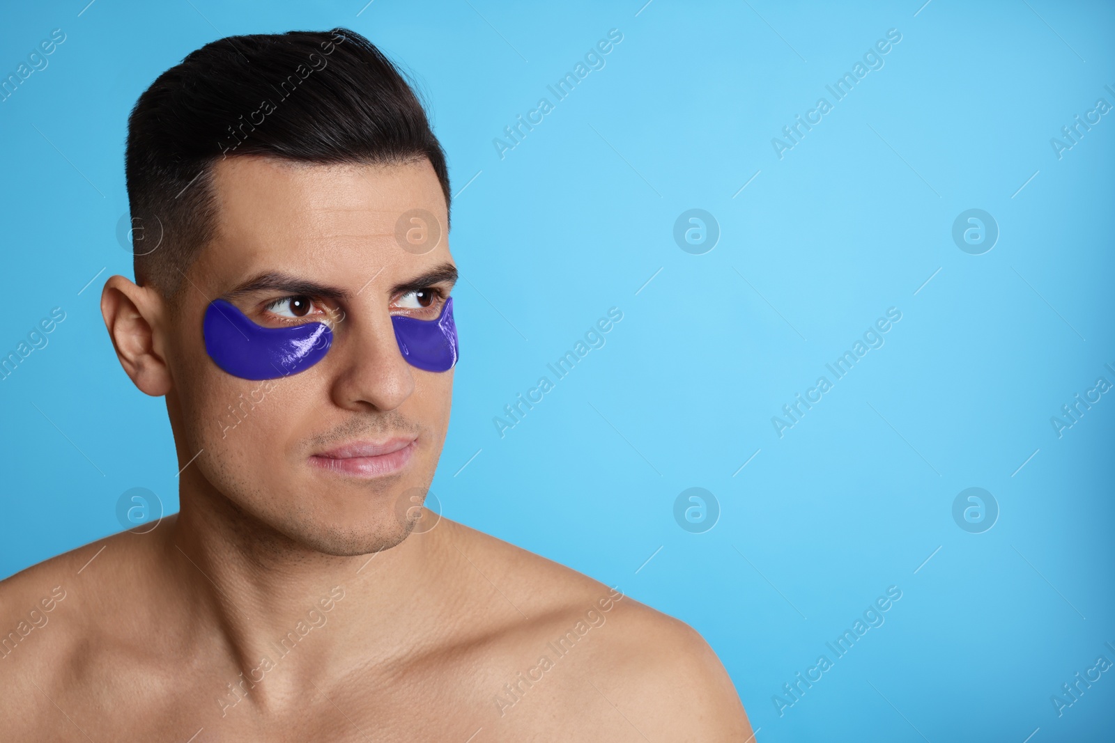 Photo of Man with under eye patches on light blue background. Space for text