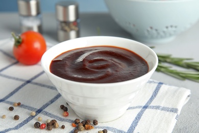 Photo of Bowl with tasty barbecue sauce on table