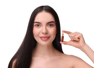 Beautiful young woman with long healthy hair holding ampoule on white background