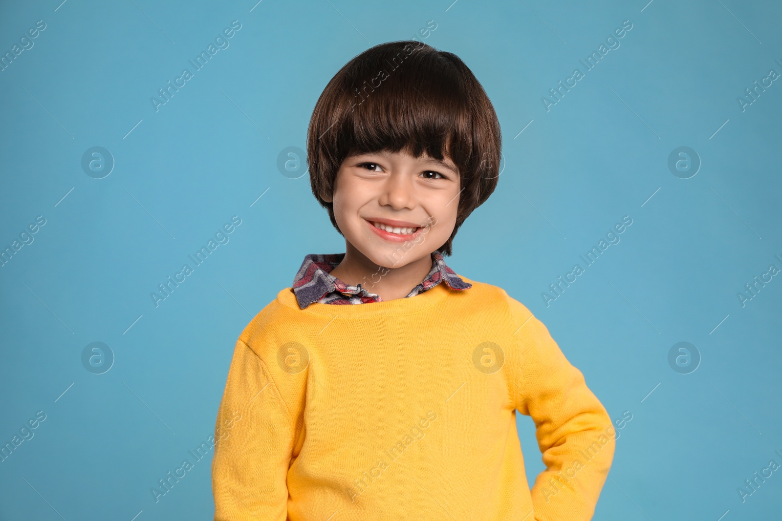 Photo of Portrait of cute little boy on light blue background