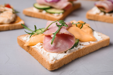 Photo of Delicious sandwiches with ham on grey table, closeup