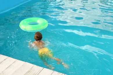 Little child with inflatable ring in outdoor swimming pool. Dangerous situation