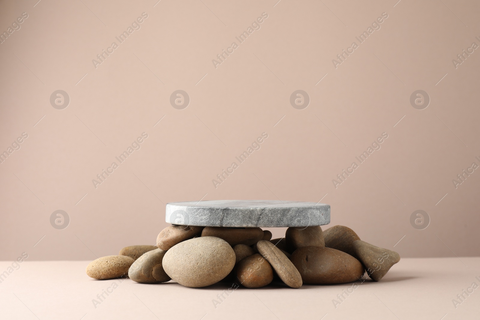 Photo of Presentation for product. Stone podium and pebbles on beige background. Space for text