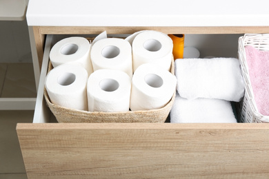 Photo of Open cabinet drawer with toilet paper rolls indoors