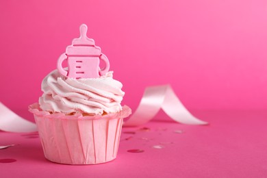 Photo of Beautifully decorated baby shower cupcake with cream and girl topper on pink background. Space for text