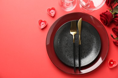 Place setting with heart shaped candles and bouquet of roses for romantic dinner on red table, flat lay. Space for text