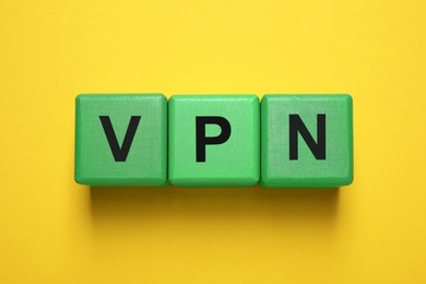 Photo of Green cubes with acronym VPN on yellow background, top view