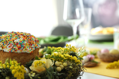 Photo of Beautiful wreath with Easter bread, closeup. Festive table setting