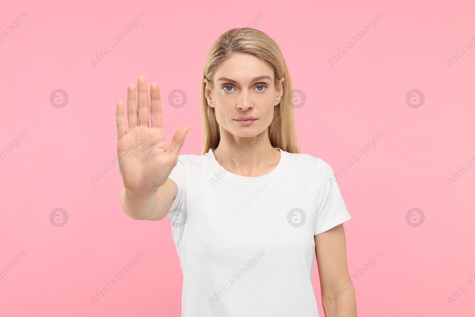 Photo of Woman showing stop gesture on pink background