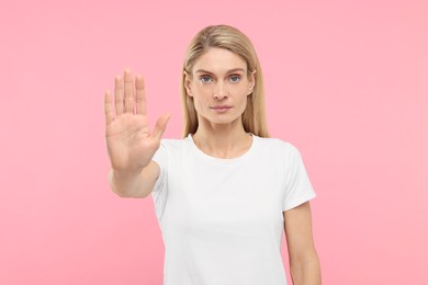 Photo of Woman showing stop gesture on pink background