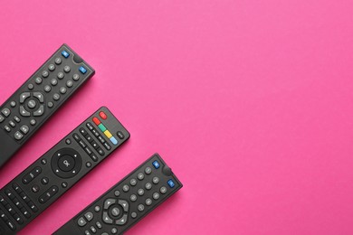 Photo of Remote controls on pink background, flat lay. Space for text