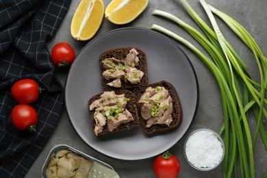 Photo of Tasty sandwiches with cod liver and different products on light grey table, flat lay