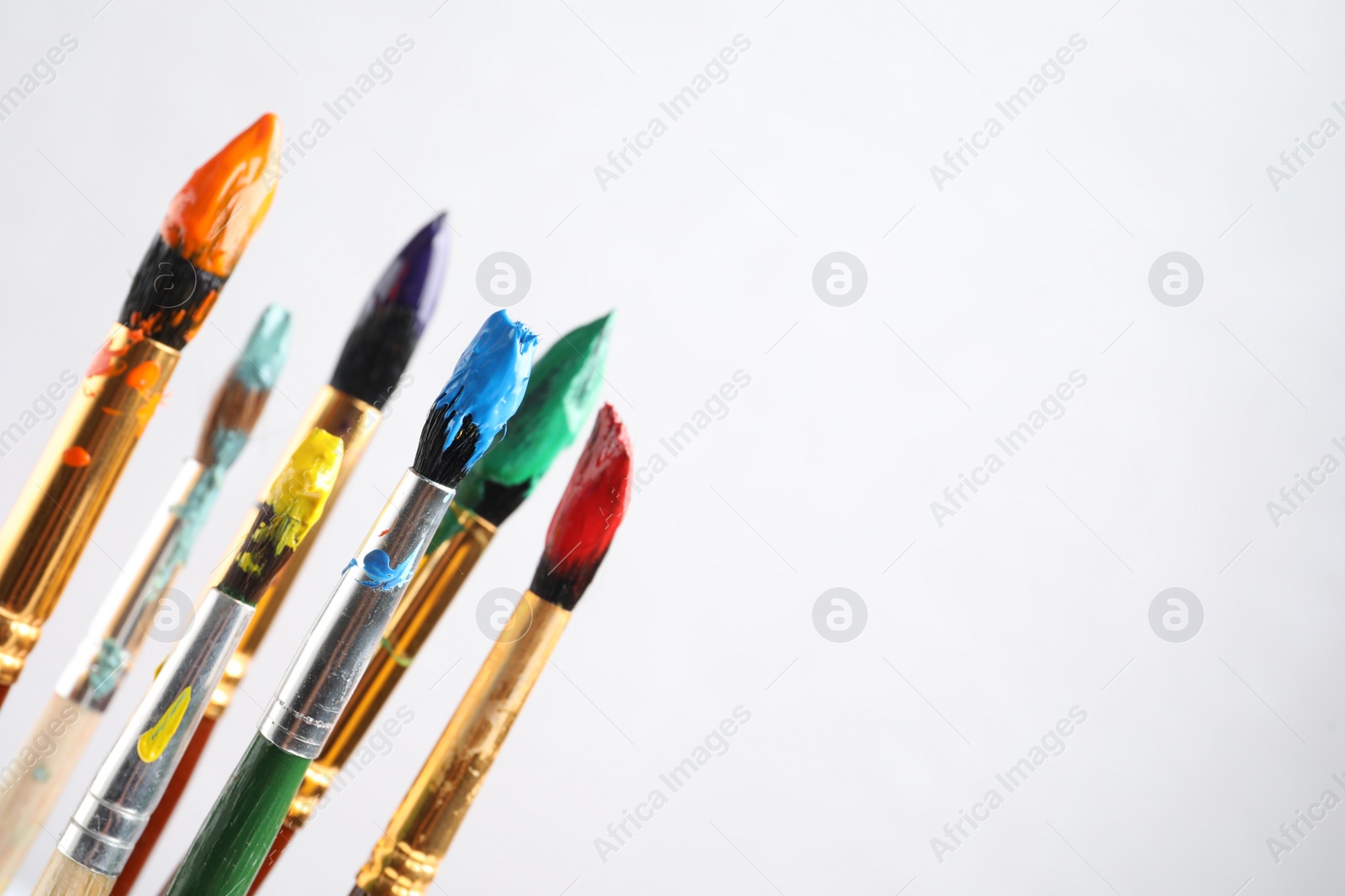 Photo of Brushes with colorful paints on light background, space for text