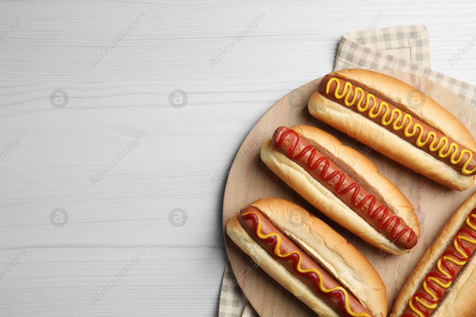 Photo of Fresh delicious hot dogs with sauces on white wooden table, top view. Space for text