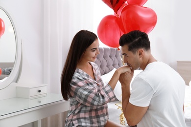 Beautiful couple with heart shaped balloons in bedroom