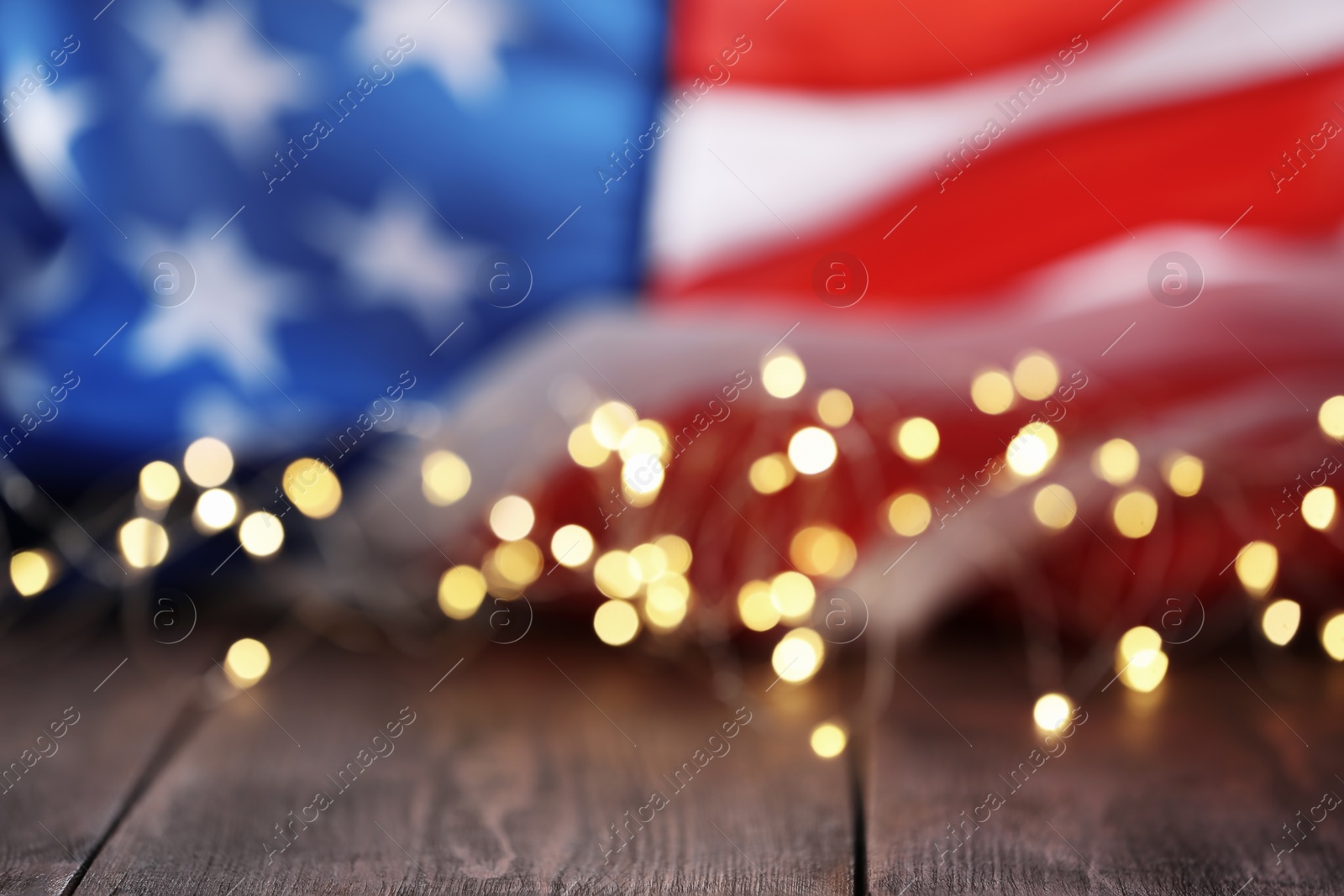 Photo of Blurred lights and American flag on wooden table. Mockup for design