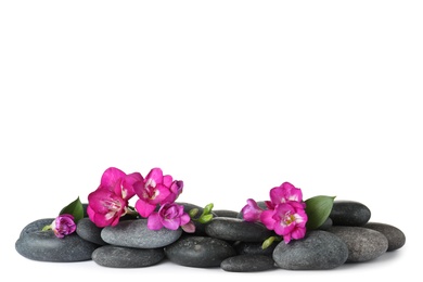 Photo of Pile of spa stones and freesia flowers on white background