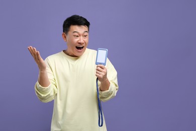 Photo of Emotional asian man with vip pass badge on purple background. Space for text
