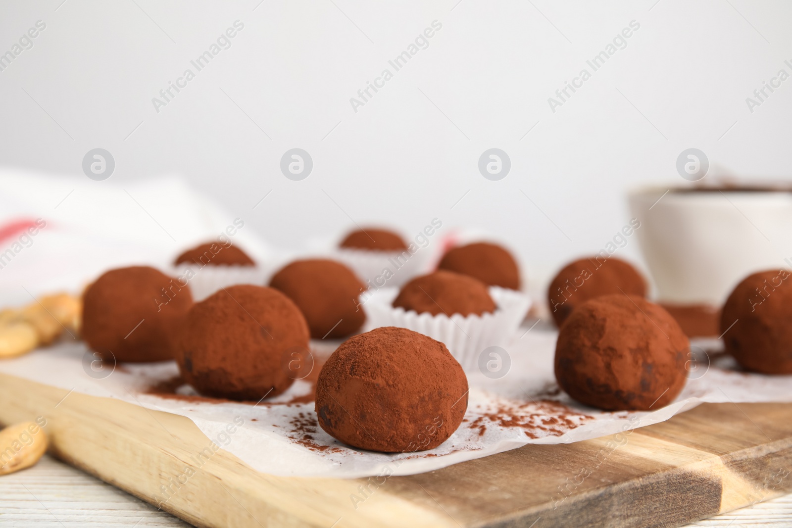 Photo of Delicious chocolate truffles powdered with cocoa on wooden board, closeup. Space for text