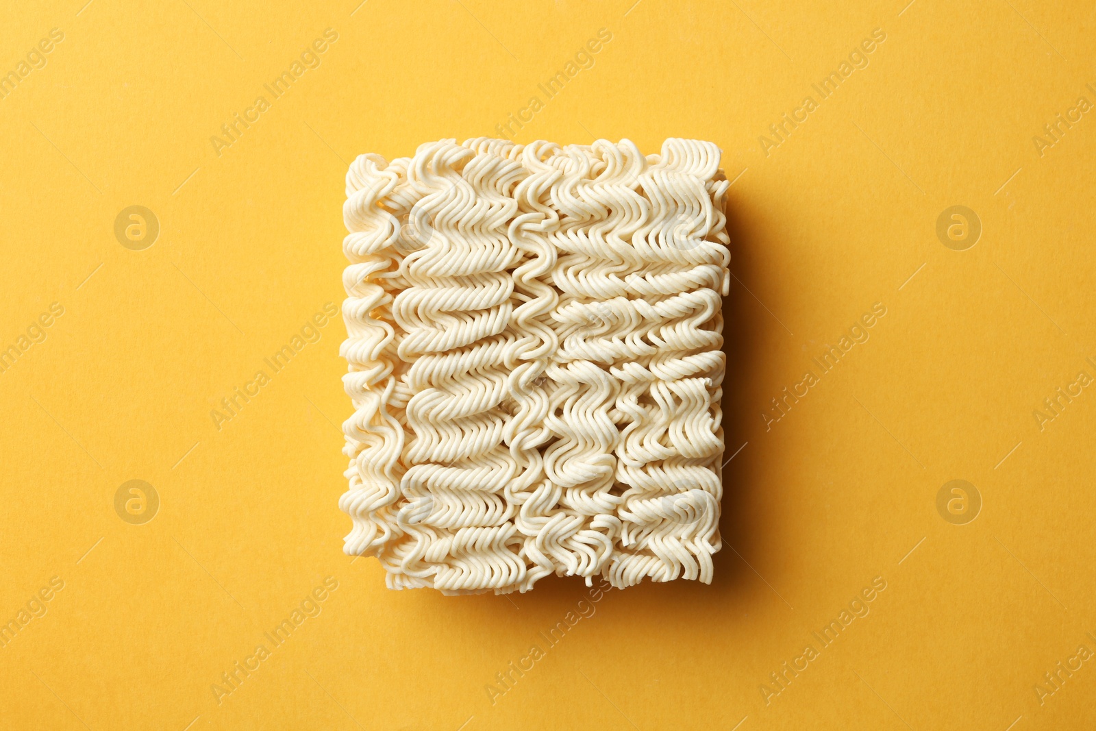 Photo of Block of quick cooking noodles on color background, top view