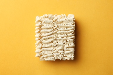 Photo of Block of quick cooking noodles on color background, top view