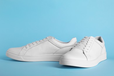 Photo of Pair of stylish white sneakers on light blue background