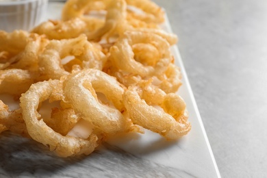 Closeup view of delicious golden breaded and deep fried crispy onion rings on marble board