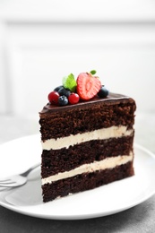 Plate with slice of chocolate sponge berry cake on grey table