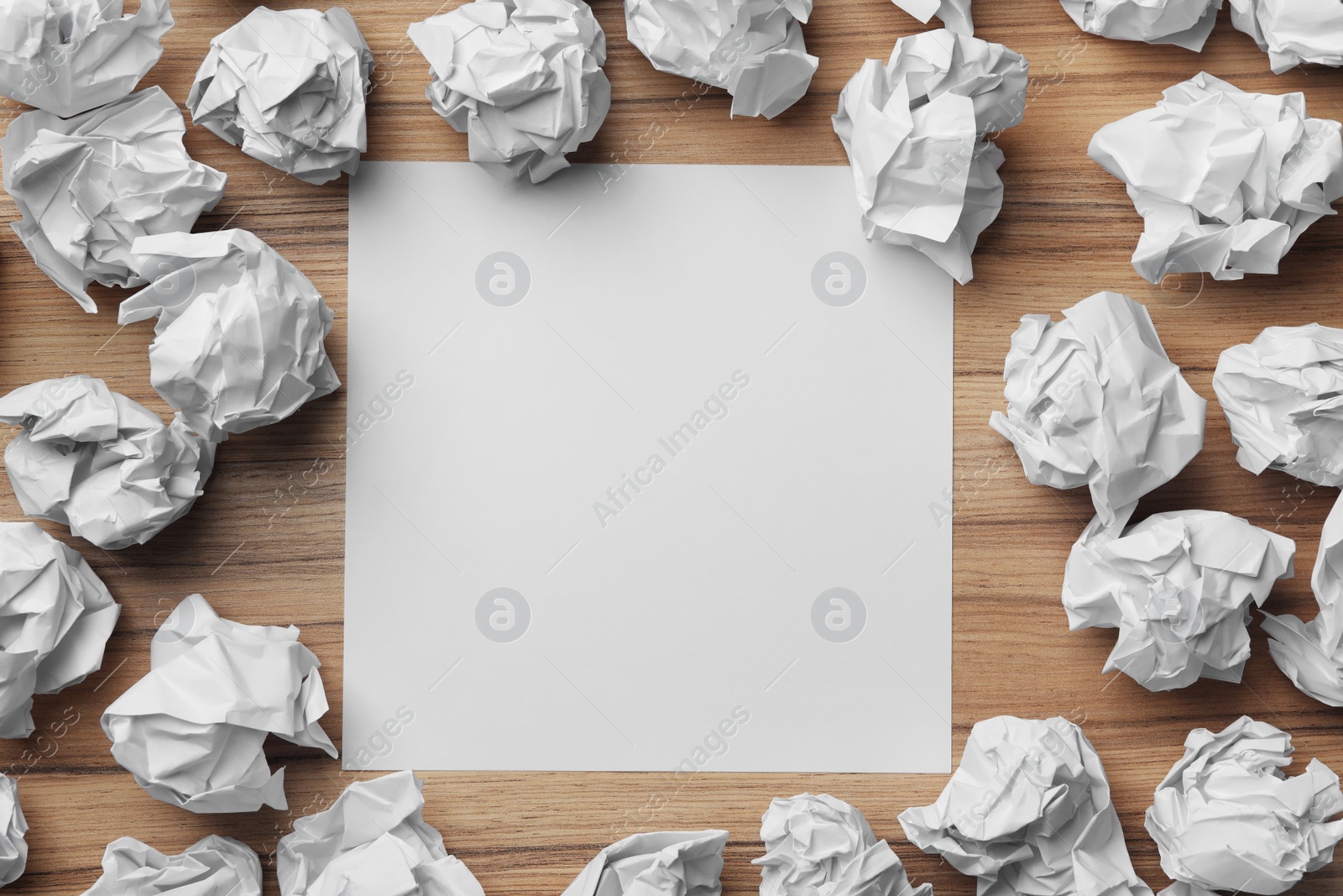 Photo of Blank sheet and crumpled paper balls on wooden table, flat lay. Space for text