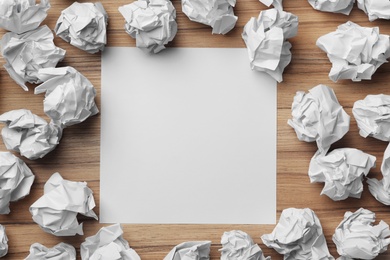 Blank sheet and crumpled paper balls on wooden table, flat lay. Space for text