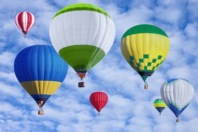 Many bright hot air balloons flying in sky