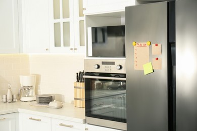 Photo of To do list and blank notes on refrigerator indoors. Space for text
